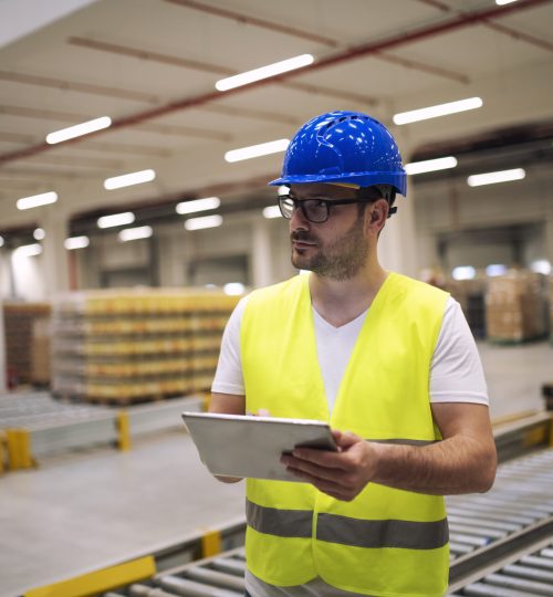 Portrait of caucasian warehouse worker with tablet standing in storage department.